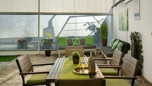 A sunlit patio with a table, chairs, and a view of the sea. - Vacation home 'Los Cipreses' with Mountain Views, Indoor Pool, Garden & Wi-Fi (Ingenio)