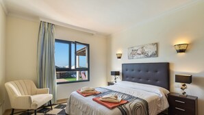 A hotel room with a bed, a chair, a nightstand, and a window with a view. - Villa Los Alisios 58 with Mountain Views, Pool, Wi-Fi, Terraces and Garden (Playa Blanca)