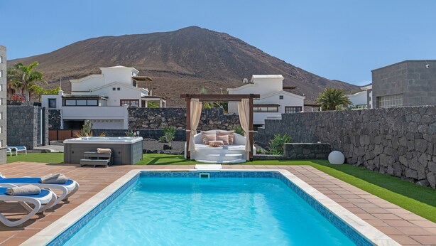 A swimming pool with a hot tub, lounge chairs, and a pergola with cushions. - Villa Los Alisios 58 with Mountain Views, Pool, Wi-Fi, Terraces and Garden (Playa Blanca)