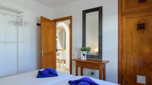 Habitación de hotel con cama, cómoda de madera, espejo y puerta que da a un baño.