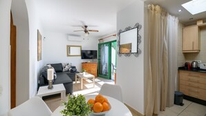 Una sala moderna con sofá, mesa de centro y comedor con mesa y sillas. Se ve una cocina con armarios y encimera.