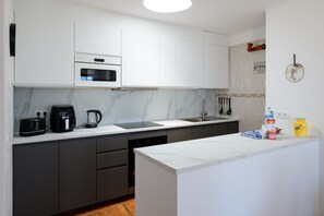 Een moderne keuken met witte kasten, een ingebouwde oven, een koffiezetapparaat en een spoelbak.