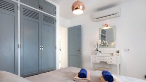 Una camera da letto con un letto, un armadio, una toeletta con specchio e un lampadario.