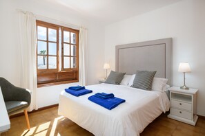 Une chambre d’hôtel avec un lit, deux tables de chevet, une chaise, une fenêtre avec des rideaux et une vue sur la plage.