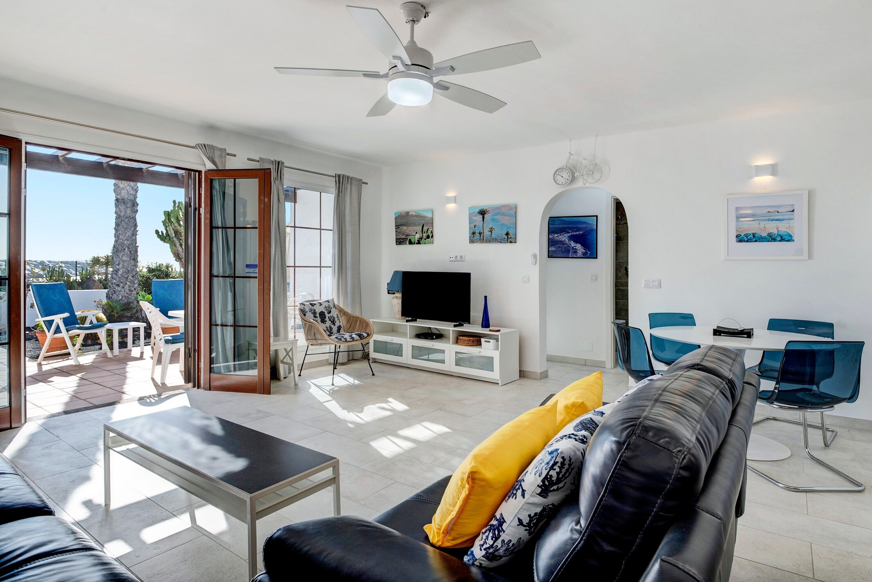 A living room with a sofa, TV, and dining area with chairs.