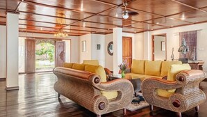 A spacious living area with a high ceiling and wooden paneling, featuring a large sofa set and two armchairs. - Camplung Beach Villa and Farmstead (Tejakula)