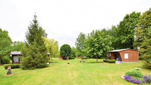 A well-maintained grassy area with a small wooden cabin and a larger building with a sloped roof. - Gemütlicher Bungalow mit Garten (Insel Poel)