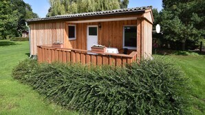 A wooden cabin with a balcony, a door, and windows. - Gemütlicher Bungalow mit Garten (Insel Poel)
