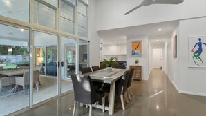 A modern kitchen with white cabinets, a dining area with a glass door leading to a patio, and a ceiling fan.