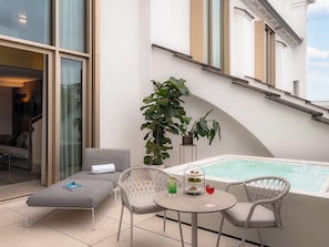 A modern outdoor seating area with a pool, lounge chairs, and a small table with drinks.