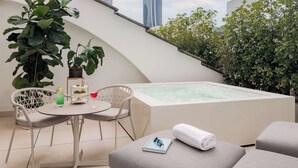 Eine Dachterrasse mit Whirlpool, Sitzgelegenheit und Topfpflanzen.