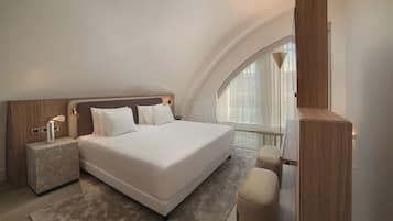 Ein modernes Schlafzimmer mit einem großen Bett, einem Nachttisch, einer Bank und einem großen Fenster.