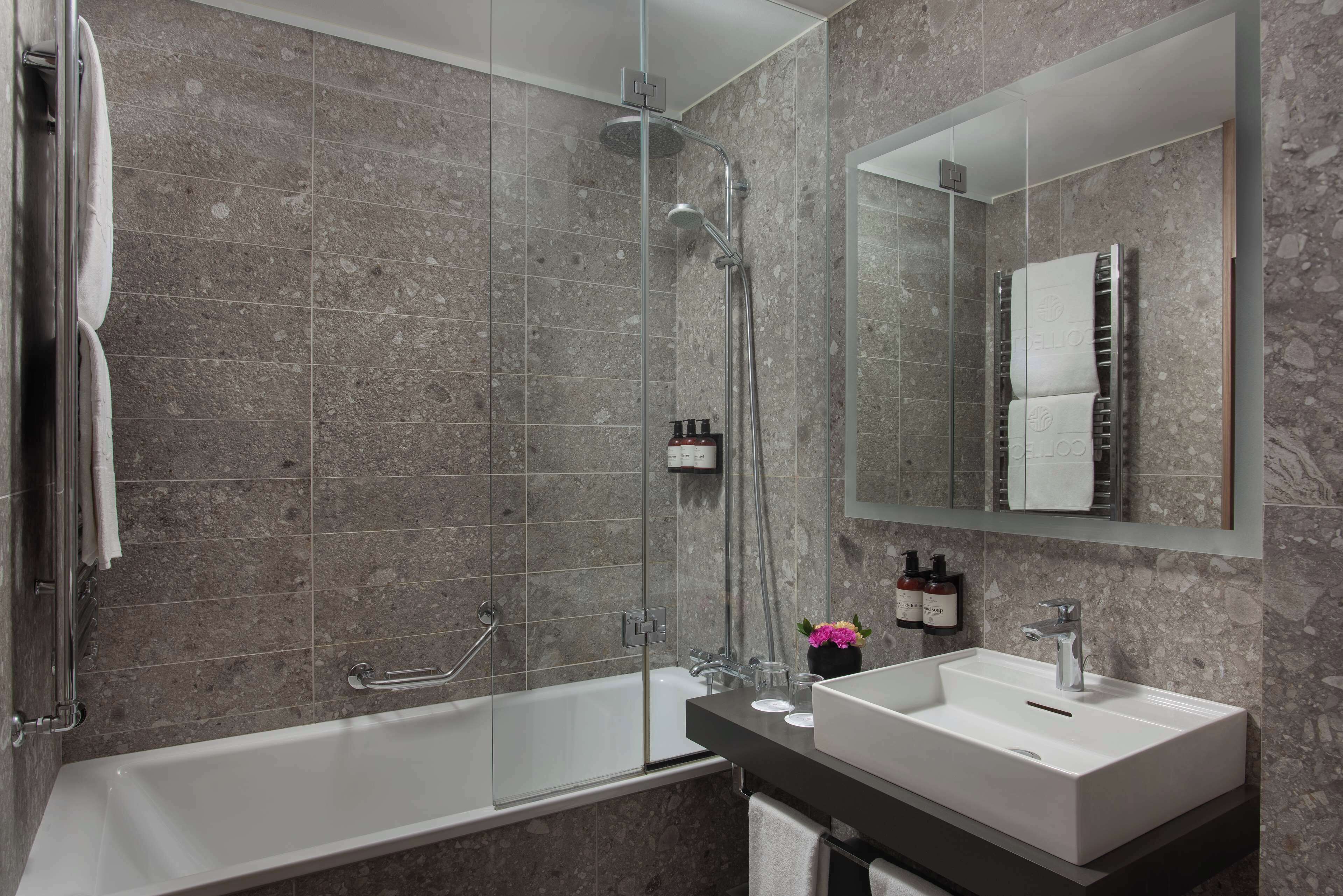 A modern bathroom with a glass-enclosed shower, a standalone bathtub, and a vanity with a sink and mirror.