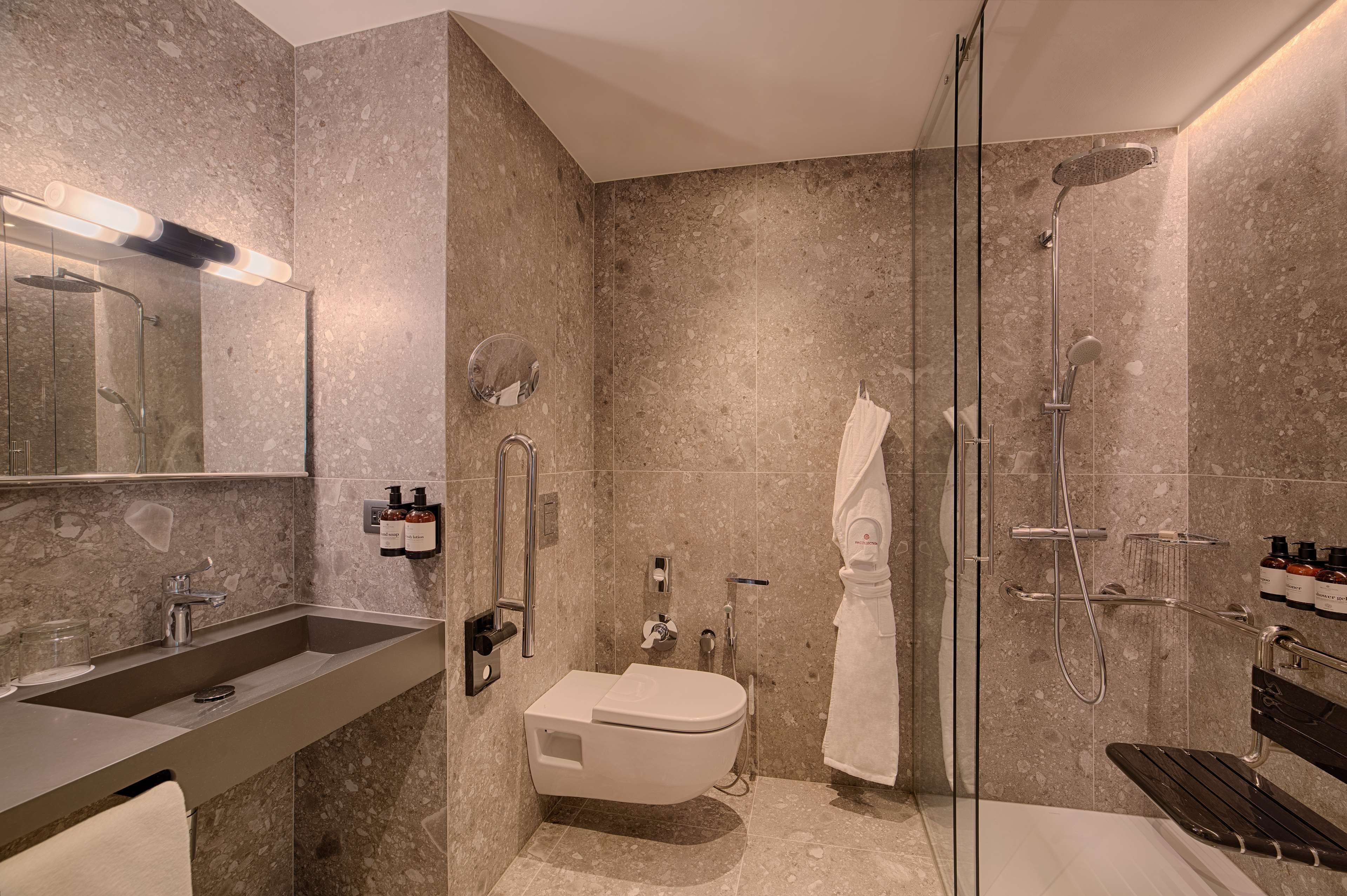 A modern bathroom with a glass shower enclosure, a built-in toilet, and a vanity with a sink and mirror.