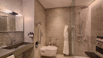 A modern bathroom with a glass shower enclosure, a built-in toilet, and a vanity with a sink and mirror.