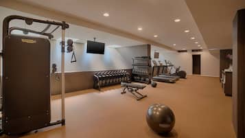 Ein modernes Fitnessstudio mit verschiedenen Trainingsgeräten, darunter ein Squat-Rack, Kurzhanteln und Laufbänder.