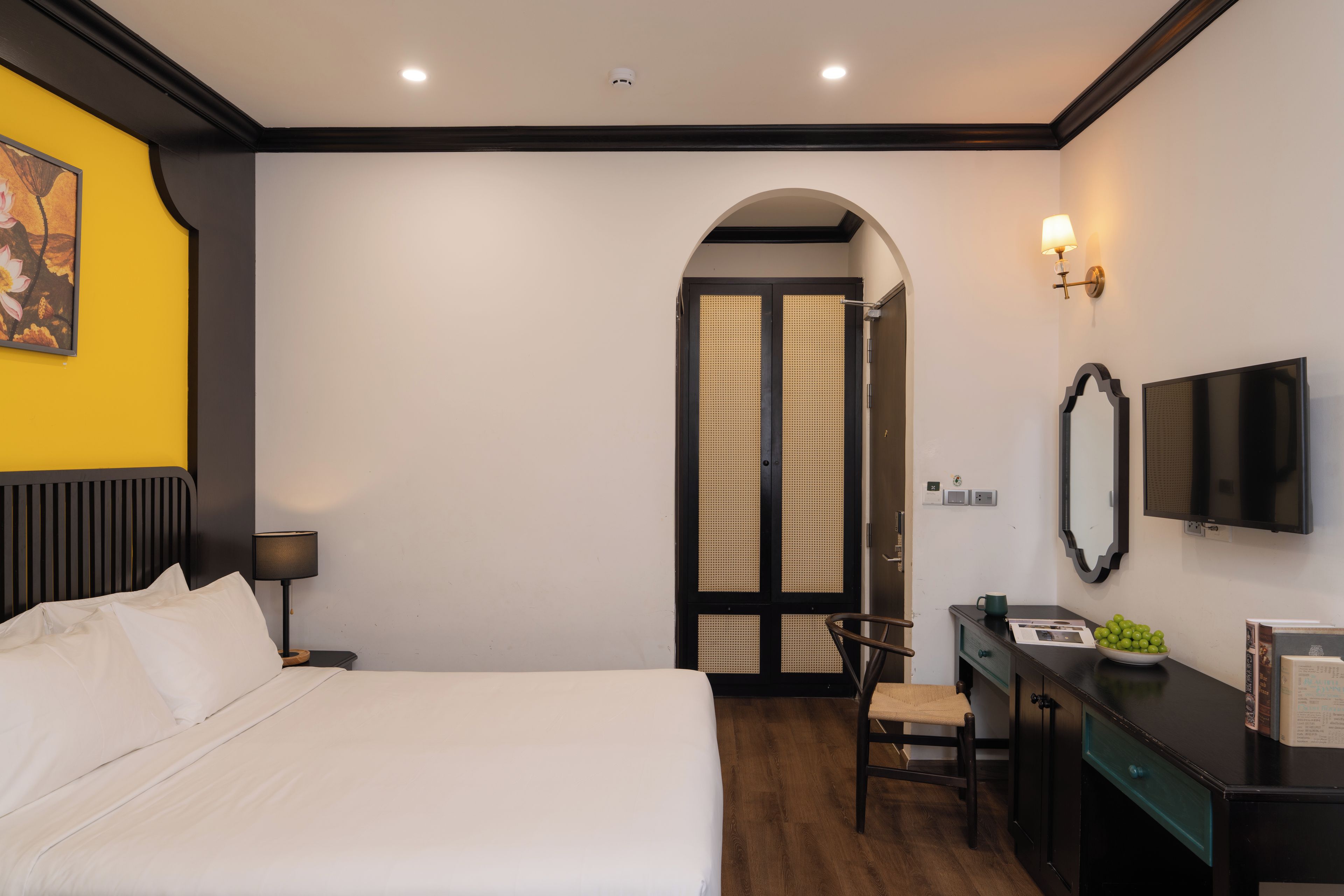 A hotel room with a bed, desk, chair, and a television.