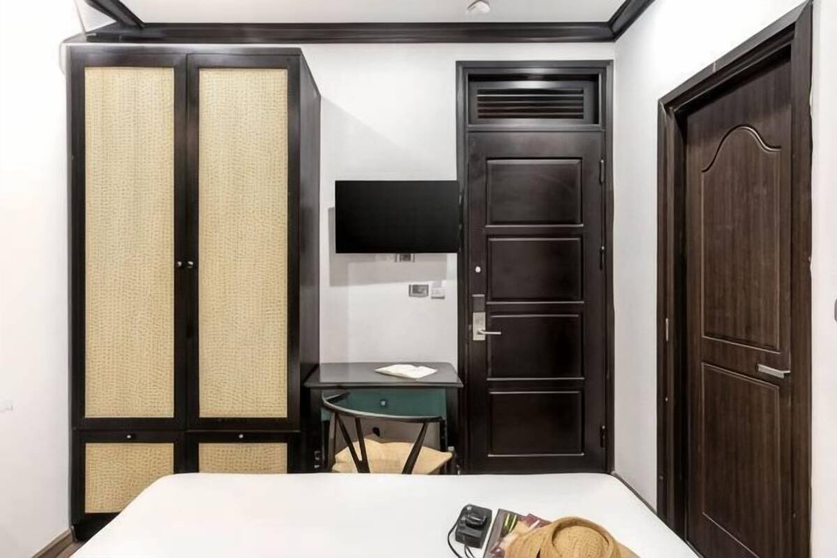 A hotel room with a bed, a desk, a TV, and a wardrobe.
