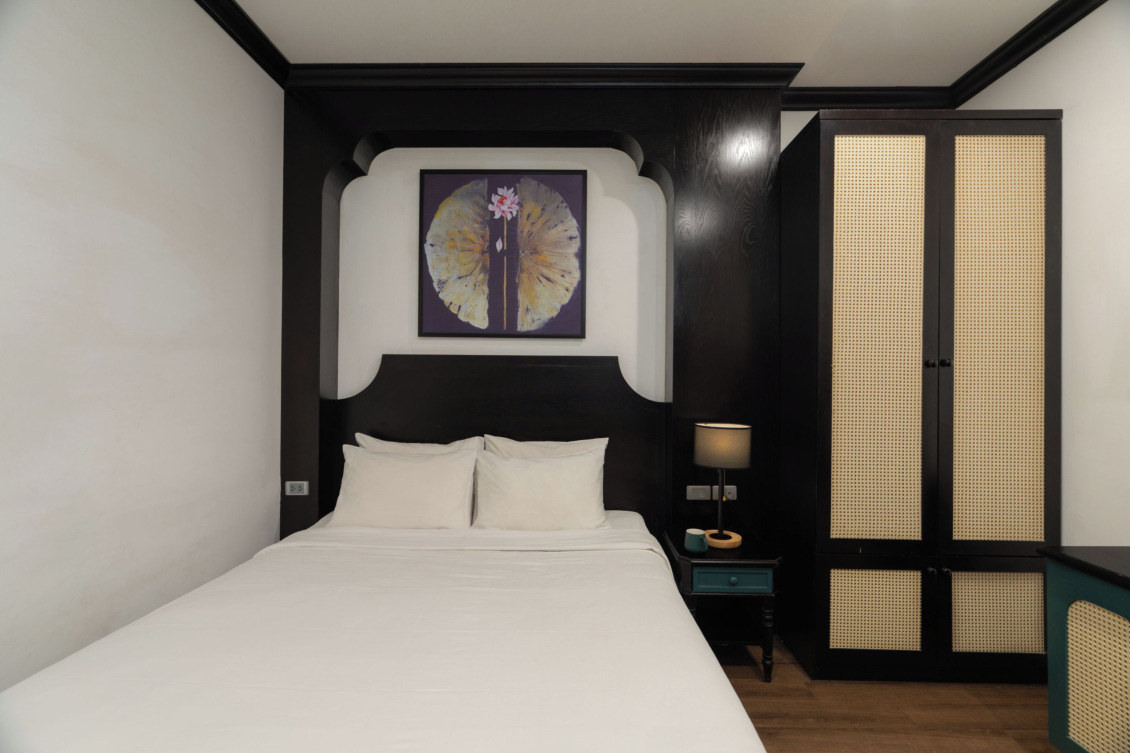 A bedroom with a bed, a nightstand, a lamp, and a wardrobe.