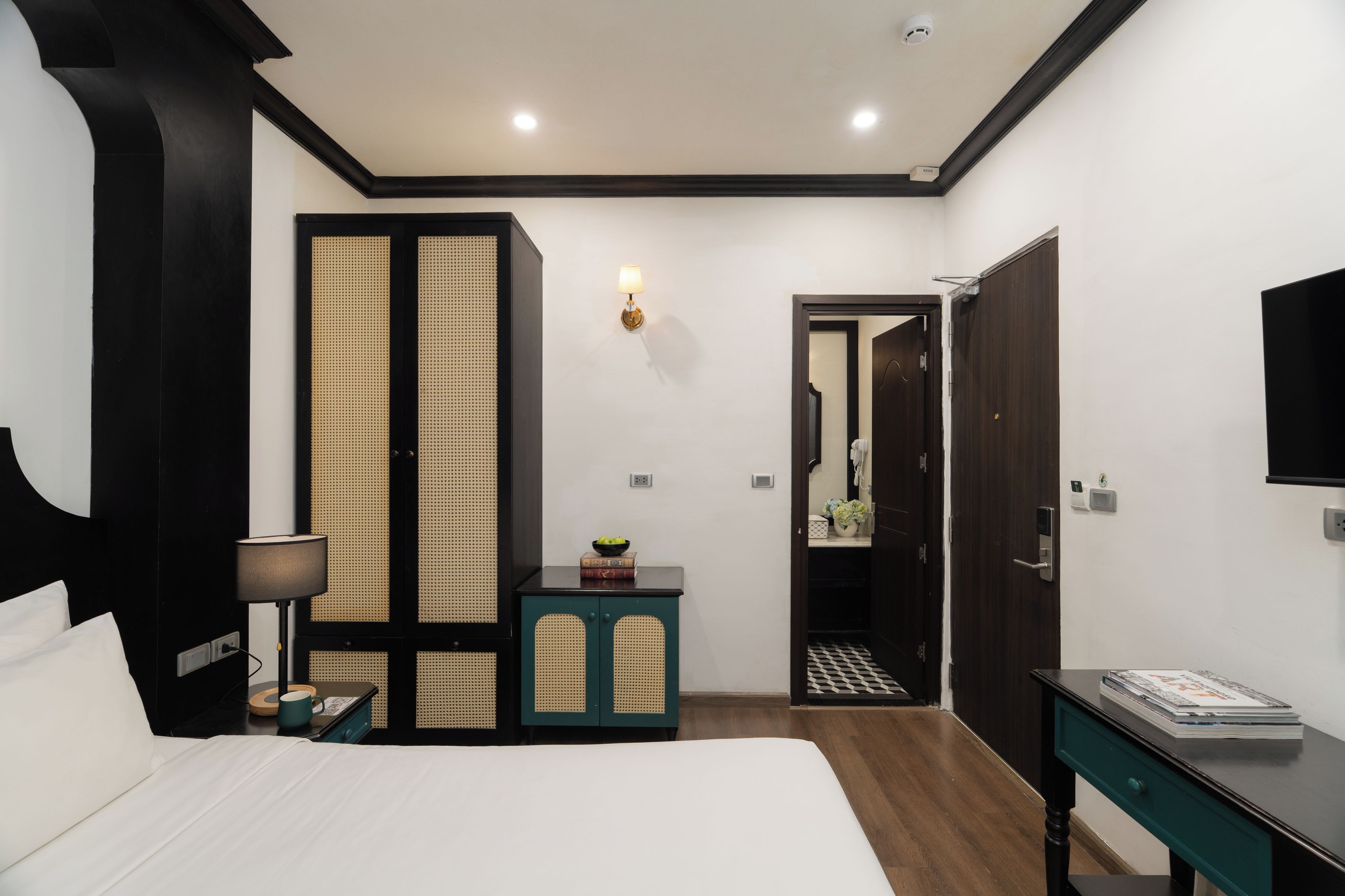 A hotel room with a bed, a desk, a wardrobe, and a bathroom visible through an open door.