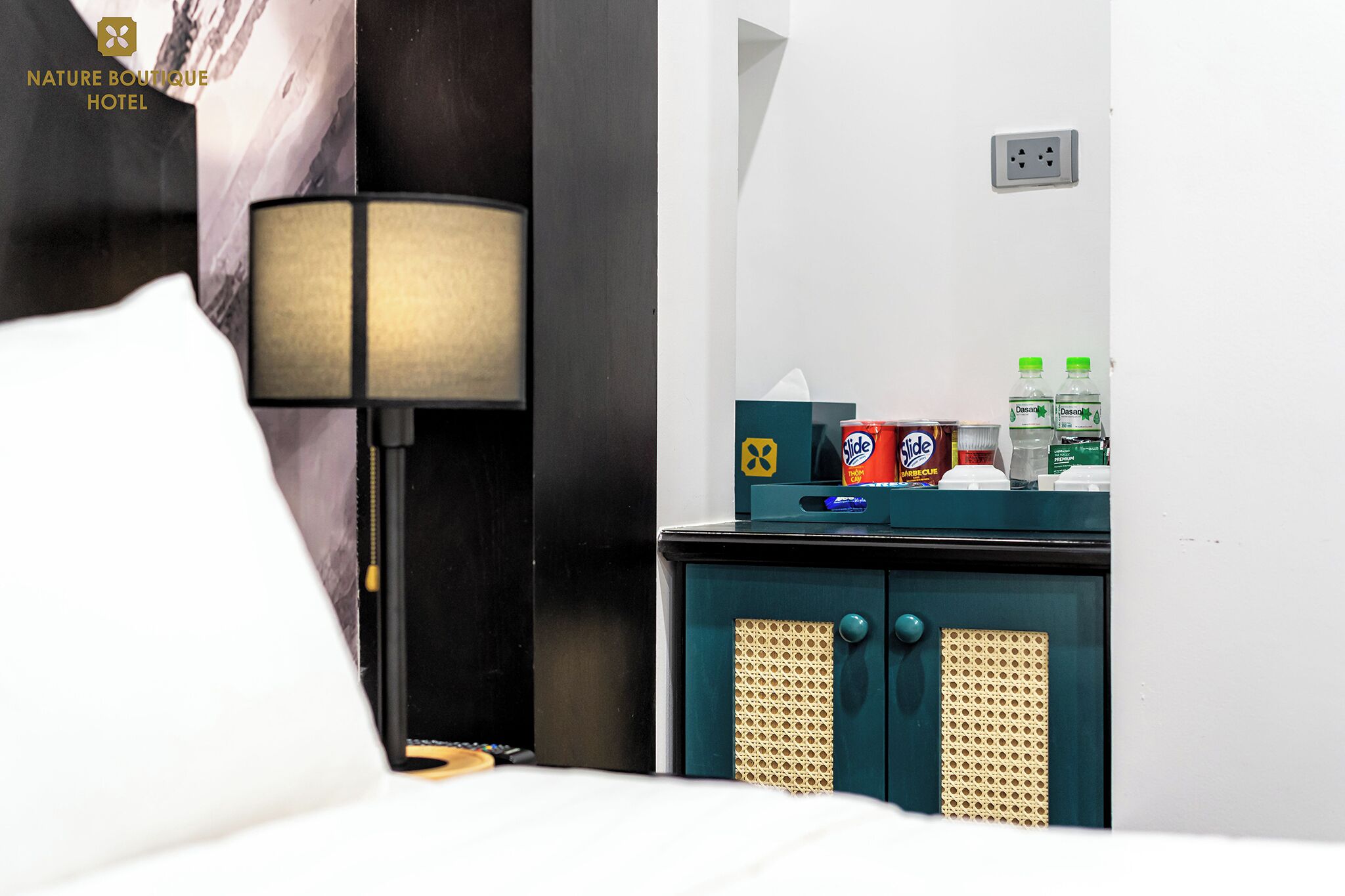 Une chambre d’hôtel équipée d’un lit, d’une lampe, d’un mini-bar et d’une prise de courant fixée au mur.