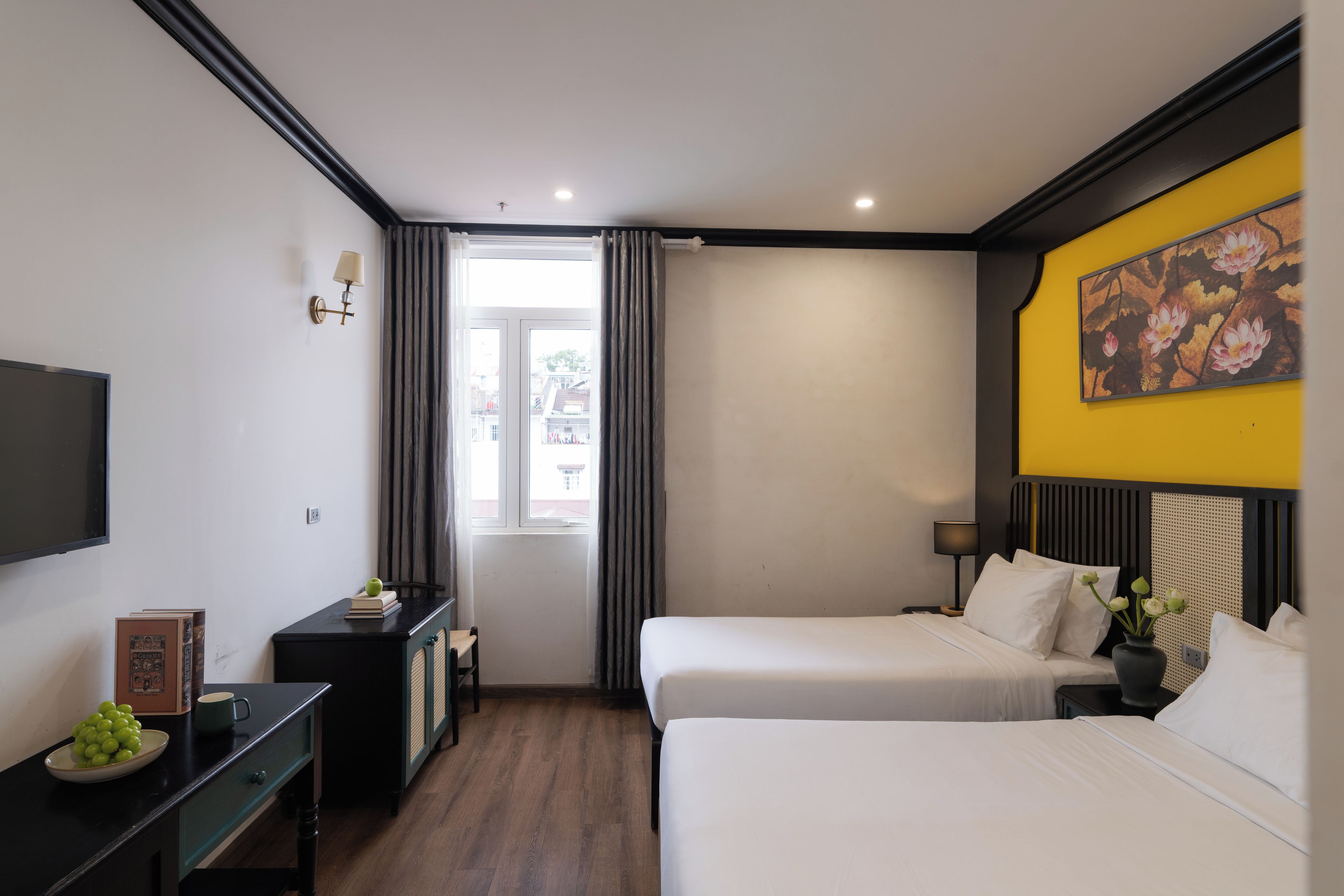 A hotel room with two beds, a desk, a television, and a window with curtains.