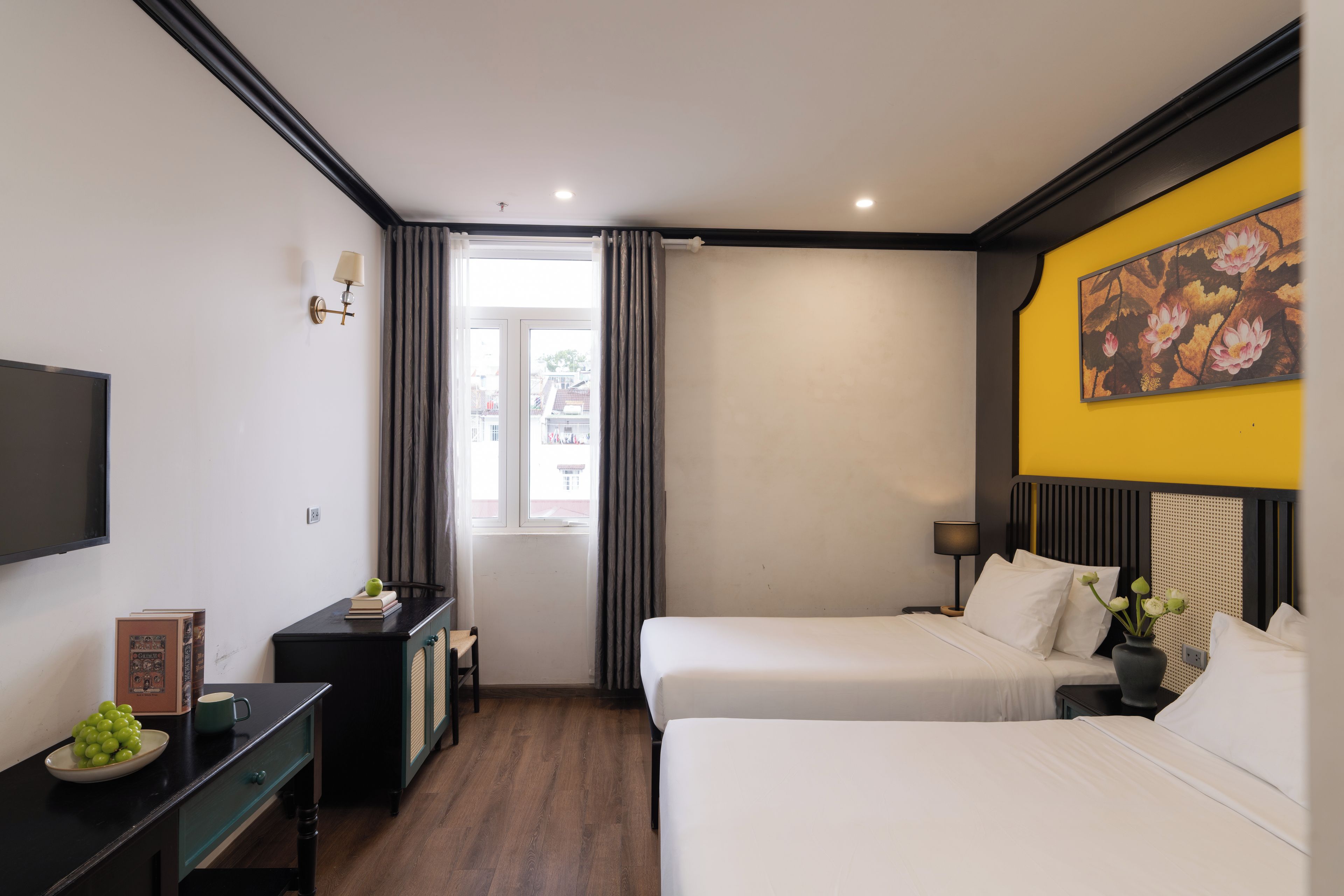 A hotel room with two beds, a desk, a TV, and a window with curtains.