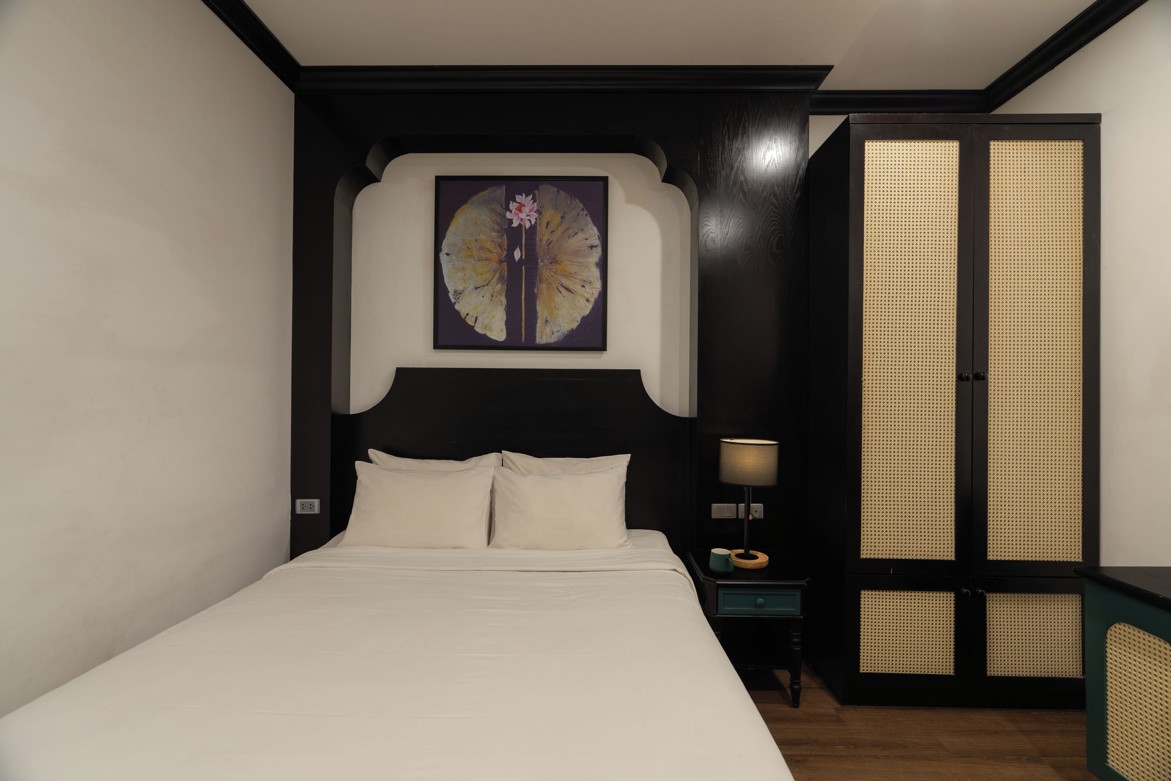 A bedroom with a bed, a nightstand, a lamp, and a wardrobe.