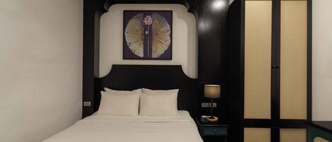A bedroom with a bed, a nightstand, a lamp, and a wardrobe.