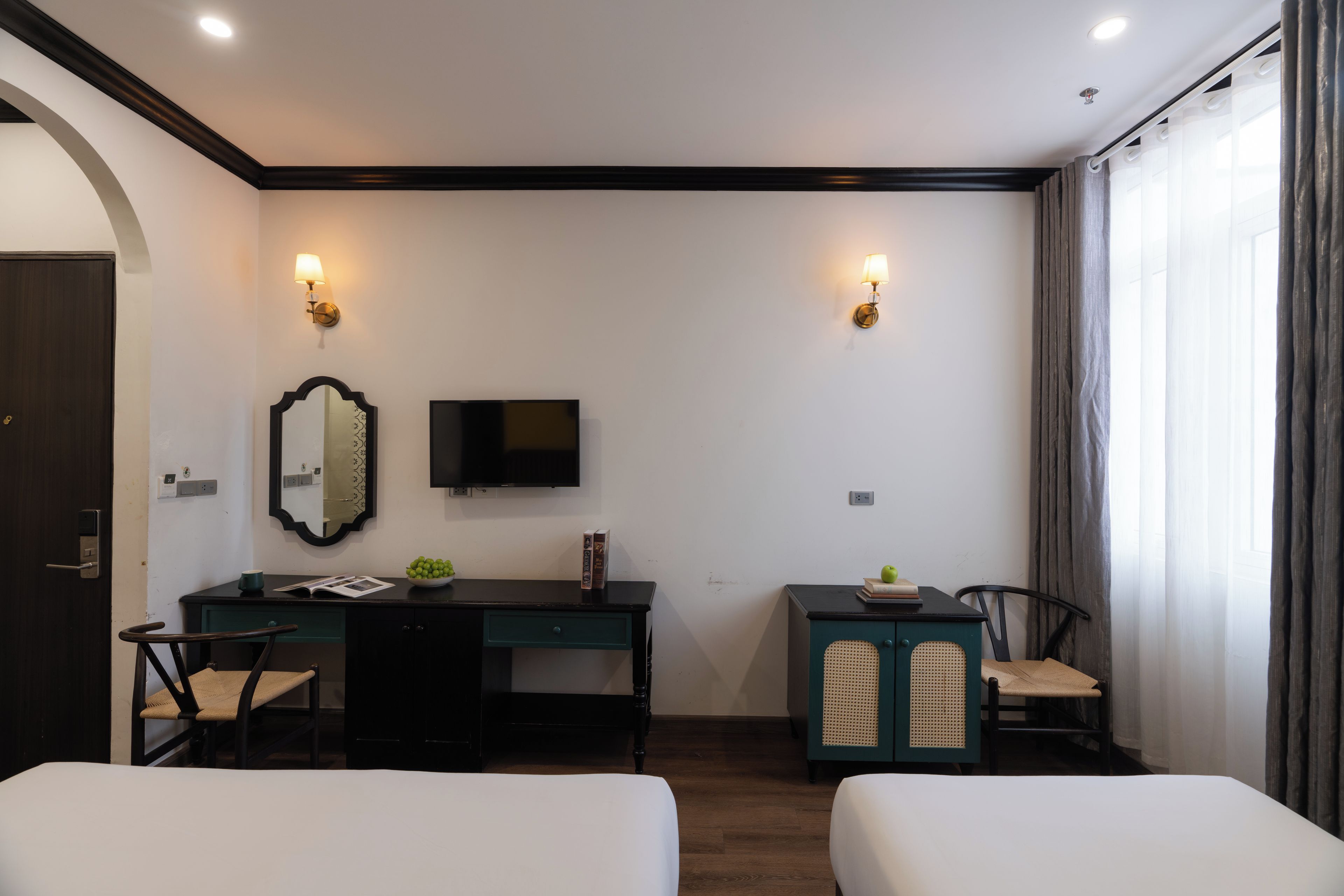 A hotel room with two beds, a desk with a mirror, a television, and a small cabinet.