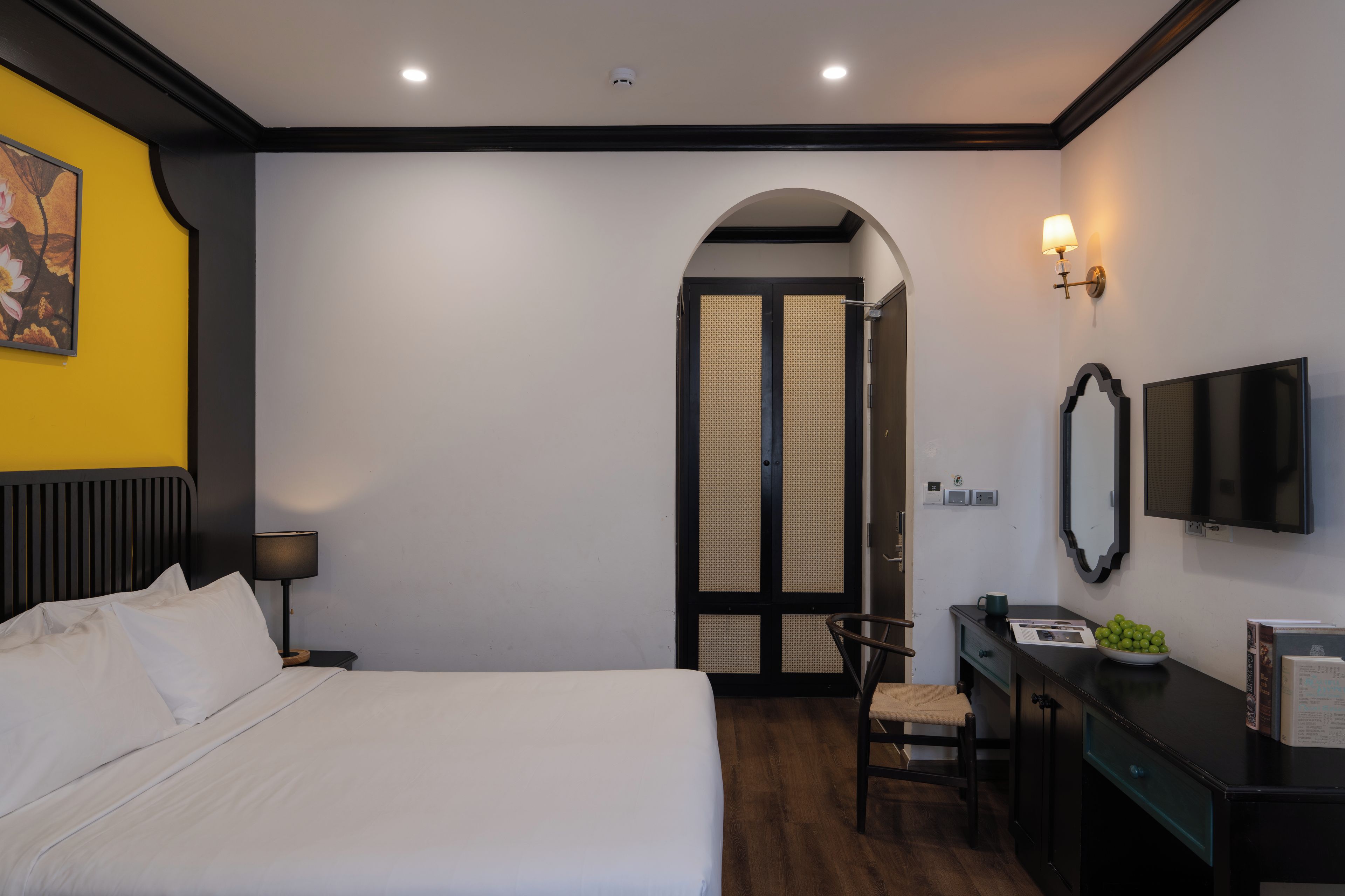 A hotel room with a bed, desk, chair, TV, and a wardrobe with a mirror.