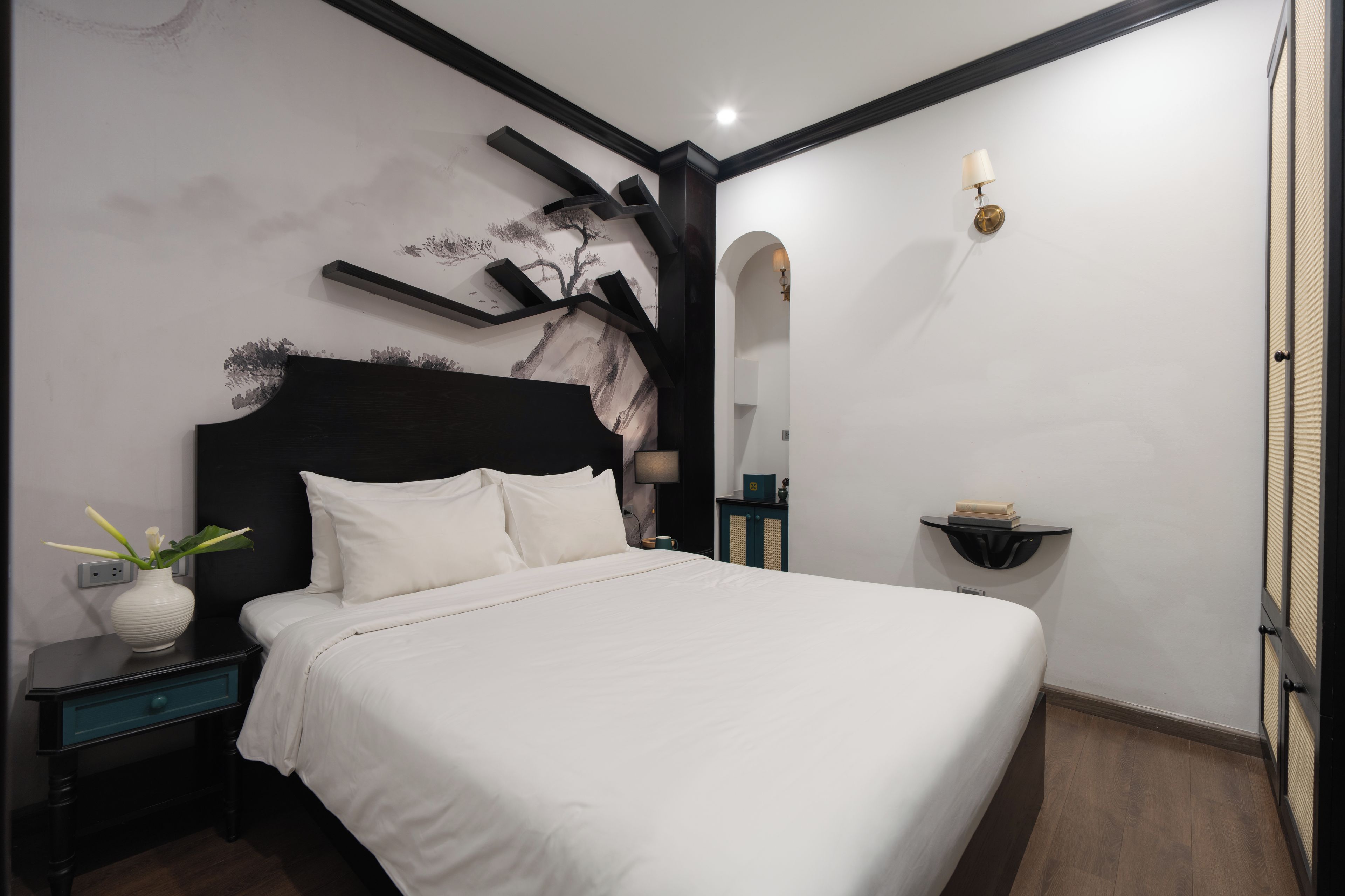 Un dormitorio moderno con una cama grande, una mesita de noche, un estante de pared y un adorno mural.