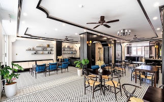 Um interior moderno com piso estampado em preto e branco, assentos azuis e diversos objetos decorativos em prateleiras.
