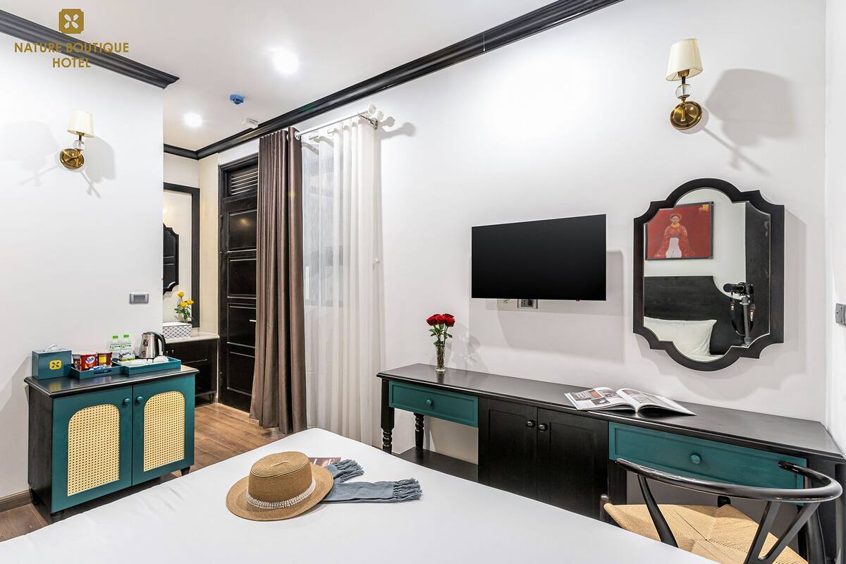 A hotel room with a bed, a desk, a TV, a mirror, and a wardrobe.