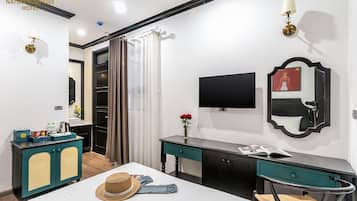 Hotellihuone, jossa on sänky, työpöytä, televisio, peili ja vaatekaappi.