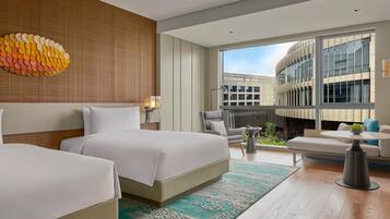 Une chambre d’hôtel moderne avec deux lits, une grande fenêtre, un balcon et une vue sur un immeuble.