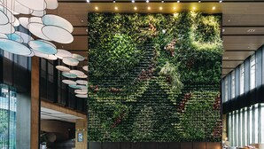 Eine moderne Lobby mit vertikaler Grünwand, Sitzgelegenheiten und zeitgemäßer Beleuchtung.