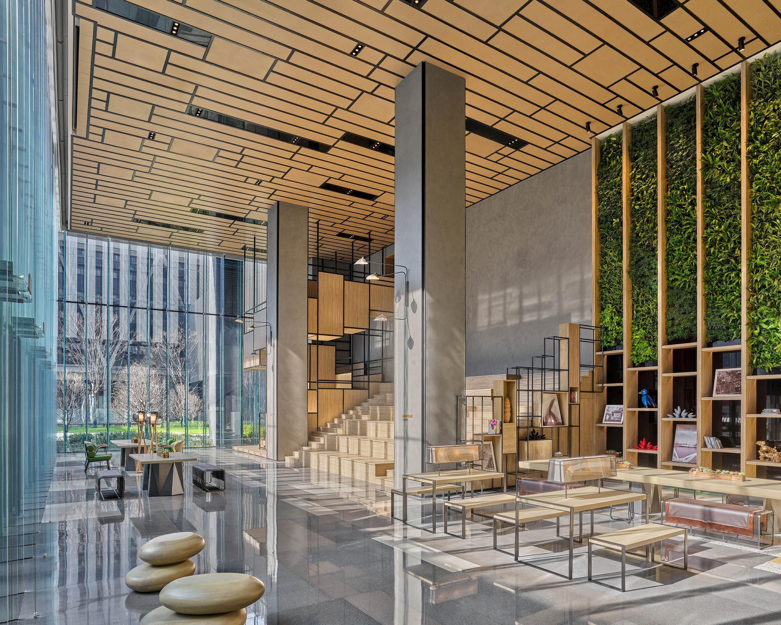A modern interior with a reflective floor, a staircase, and a wall with vertical greenery.