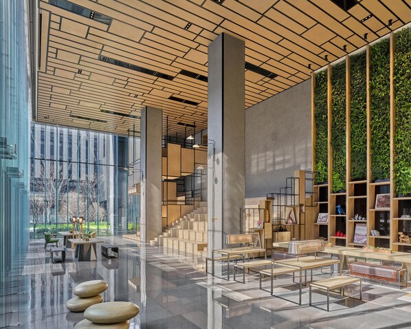 A modern interior with a reflective floor, a staircase, and a wall with vertical greenery.