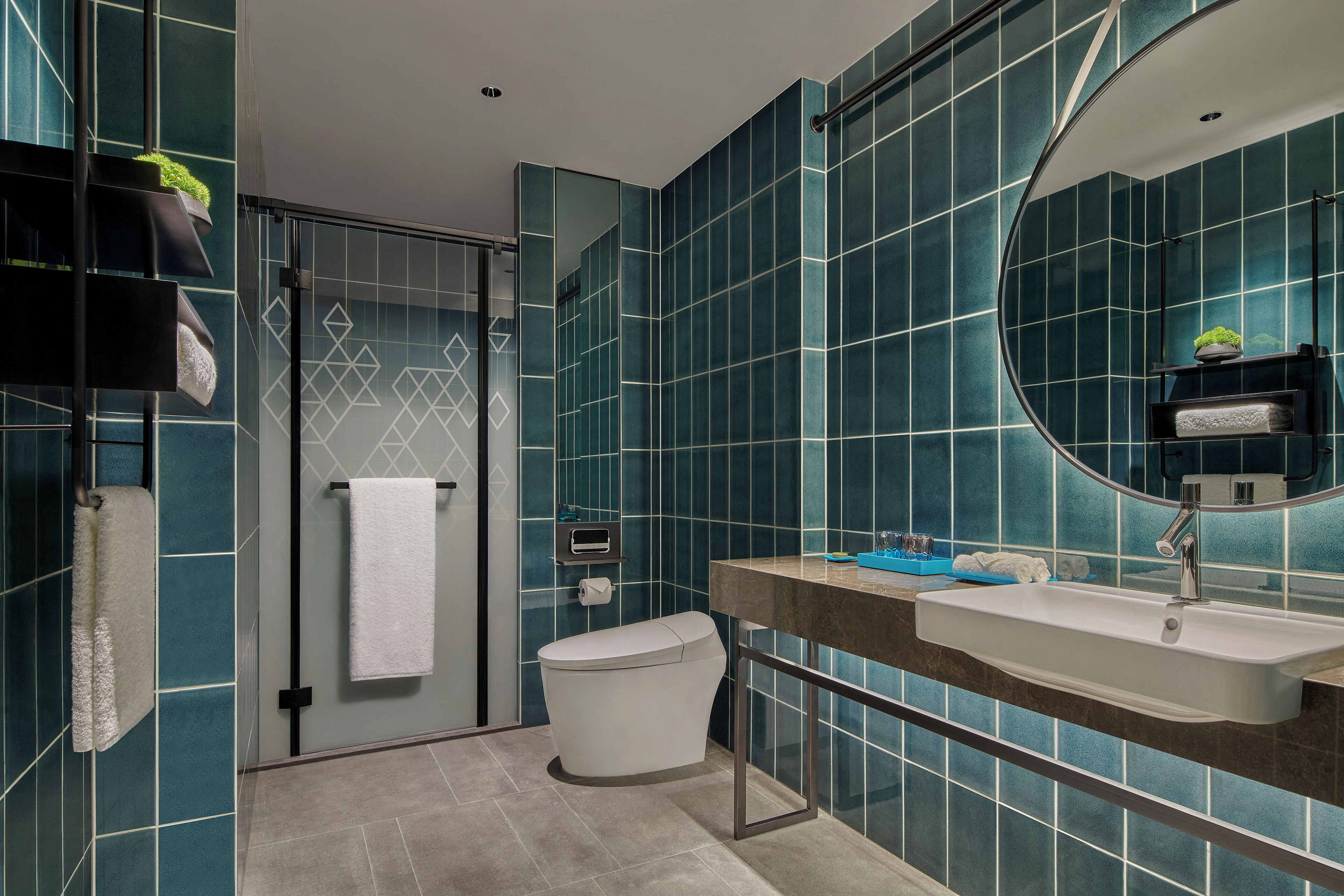 A modern bathroom with a large mirror, a white sink, and a glass shower enclosure.