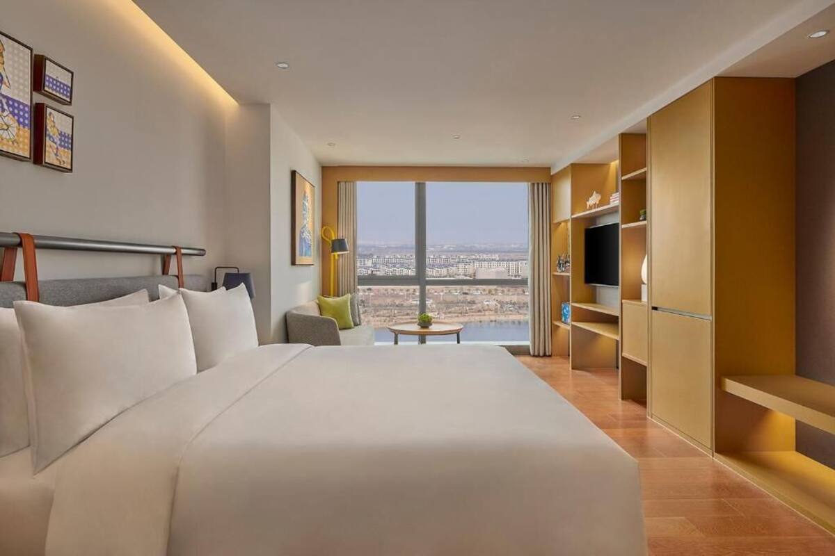 Une chambre d’hôtel avec un grand lit, un canapé, une télévision et une vue sur la ville.