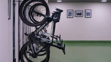 Una bicicletta montata su un supporto a parete in una stanza con pavimento verde e quadri appesi al muro.
