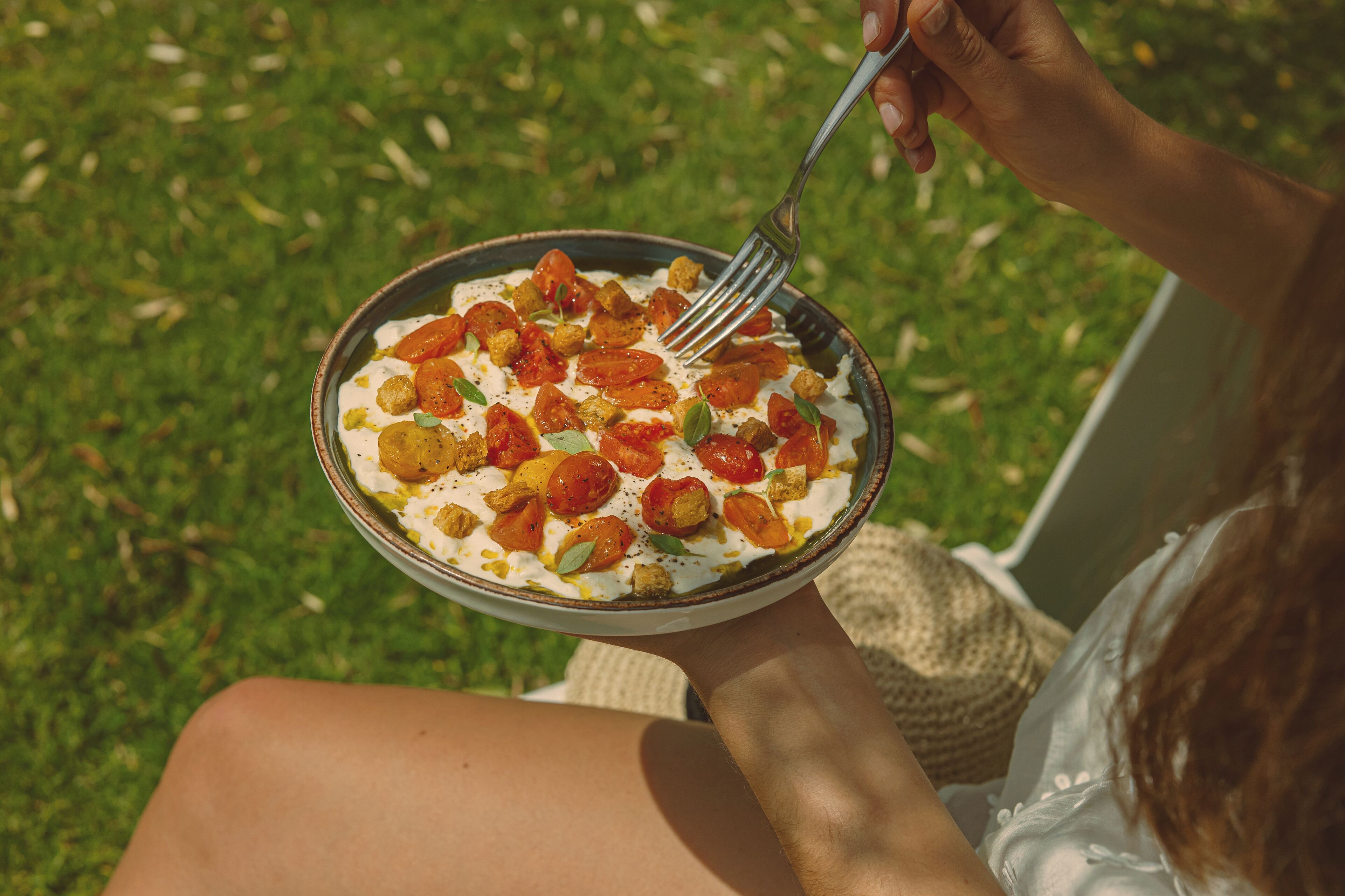 Una persona sosteniendo un plato de comida al aire libre.