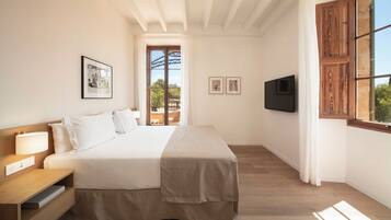A bedroom with a bed, bedside table, lamp, TV, and large window.