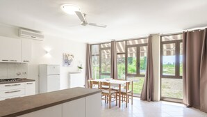 Een moderne keuken met witte kastjes, een fornuis en een eethoek met een tafel en stoelen.