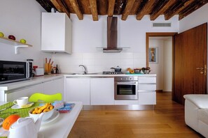 A modern kitchen with white cabinetry, a stainless steel range, and a built-in oven.