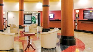 Un hall d’entrée doté de grandes colonnes en bois, d’un comptoir de réception et d’espaces aménagés avec des sièges.