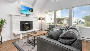 Ein modernes Wohnzimmer mit Kamin, einer Couch, einem Couchtisch und einem Fernseher über dem Kamin.
