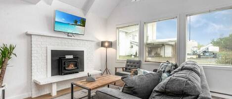 A modern living room with a fireplace, a sofa, a coffee table, and a TV mounted above the fireplace.