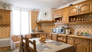 A kitchen with wooden cabinets, a microwave, a toaster, and a clock on the wall. - Atypical old house in Montreuil. (Montreuil)